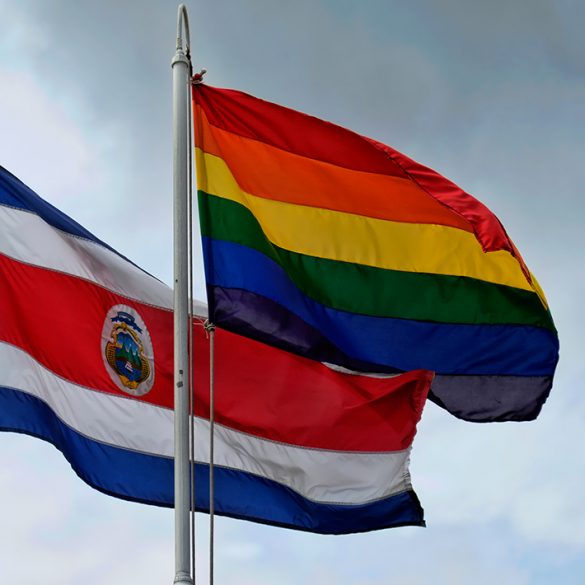 A Costa Rican flag waves beside a rainbow pride flag outside the presidential palace in San José.