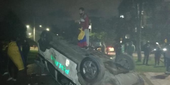 Violent protests erupted this month in Colombia after a civilian died in police custody. An overturned police car at a protest in Bogotá is pictured above. // File Photo: @petrogustavo via Twitter.