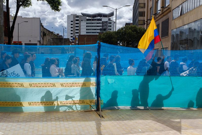 Protesters in Colombia behind fencing hold the Colombian flag