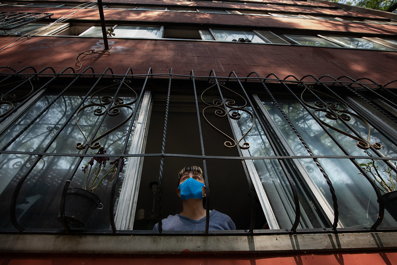 A man with a mask sits in his house in Mexico behind barred windows