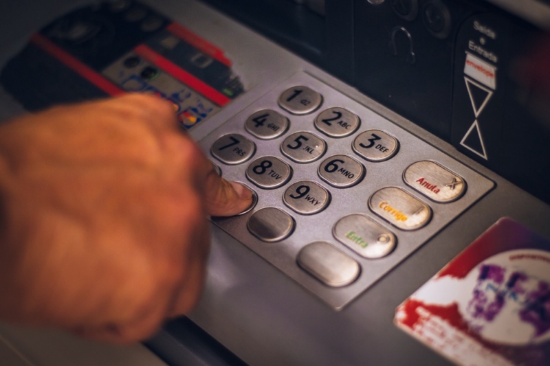 A hand pressing buttons on an ATM machine.