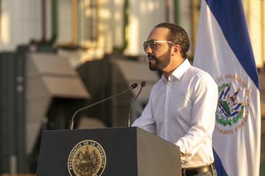Salvadoran President Nayib Bukele, wearing sunglasses, speaks at a podium.