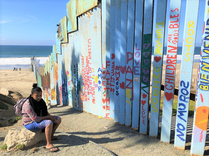Female asylum seeker sitting in front of a fence