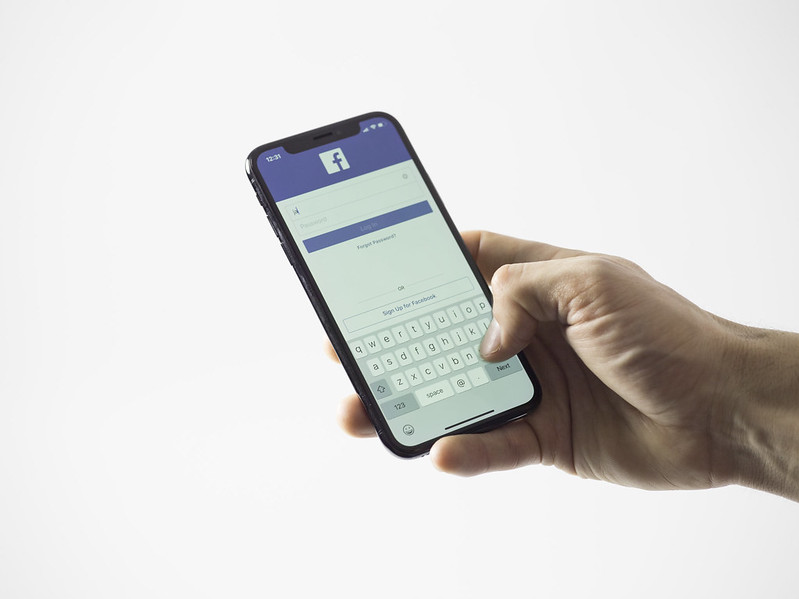 Person's hand hold a smartphone with the screen open to the Facebook app