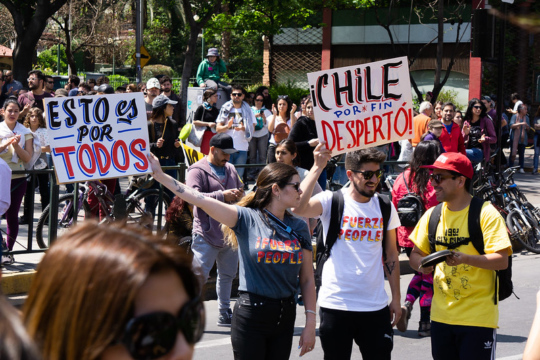 Chilean protesters on the street in 2019 holding signs that say 