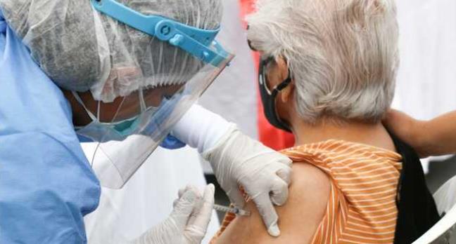 A nurse vaccinates a woman.