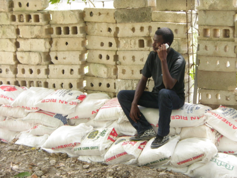 Man in Haiti sits on bags of rice from the United States