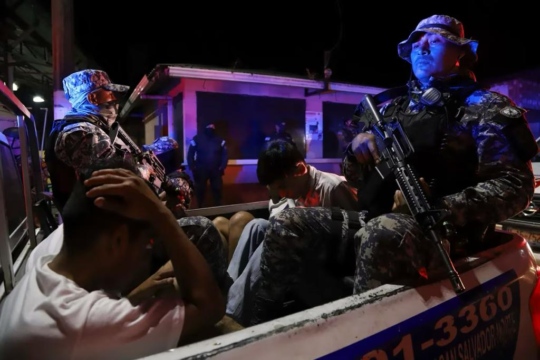 Armed men in military uniforms in a truck carrying detainees