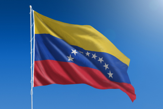 The National flag of Venezuela blowing in the wind in front of a clear blue sky