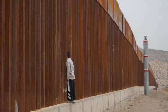 Foto de un hombre joven a la frontera México-Estados Unidos